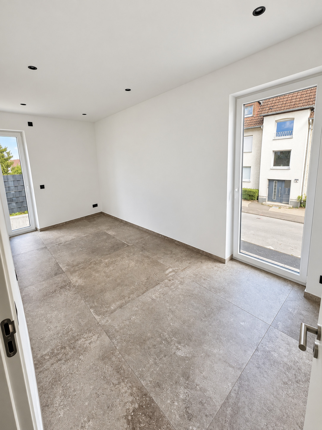 Zweites Zimmer im Übergabezustand mit bodentiefem Fenster